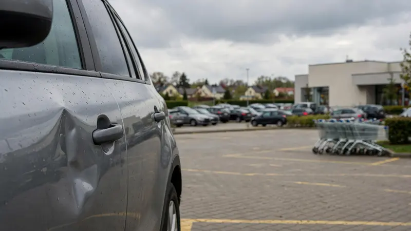 Wgniecenie parkingowe na drzwiach SUV-a na parkingu przy centrum handlowym